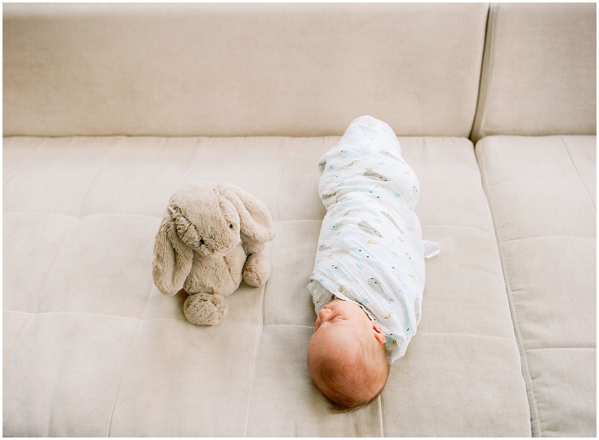 baby boy swaddled in blanket is sleeping on the couch with his toy grey bunny in Hoboken NJ