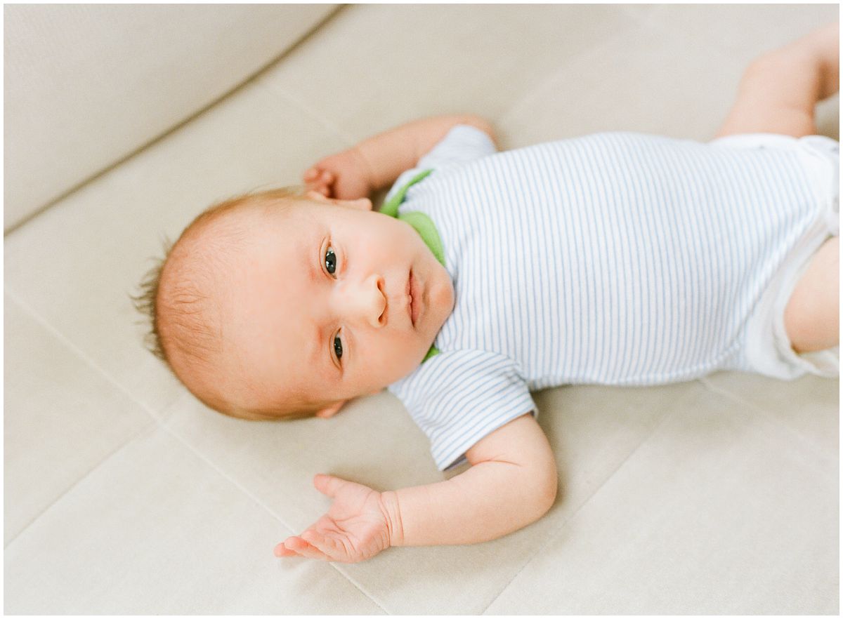 baby boy is waking up and stretching on the hilt couch in his living room during the newborn session in Hoboken NJ