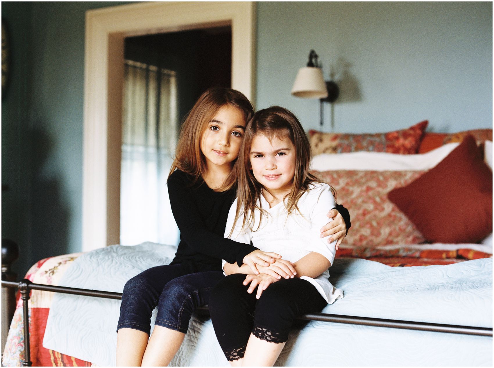 Lifestyle Family Photography with two cute sisters sitting on a bed of their Maplewood NJ home