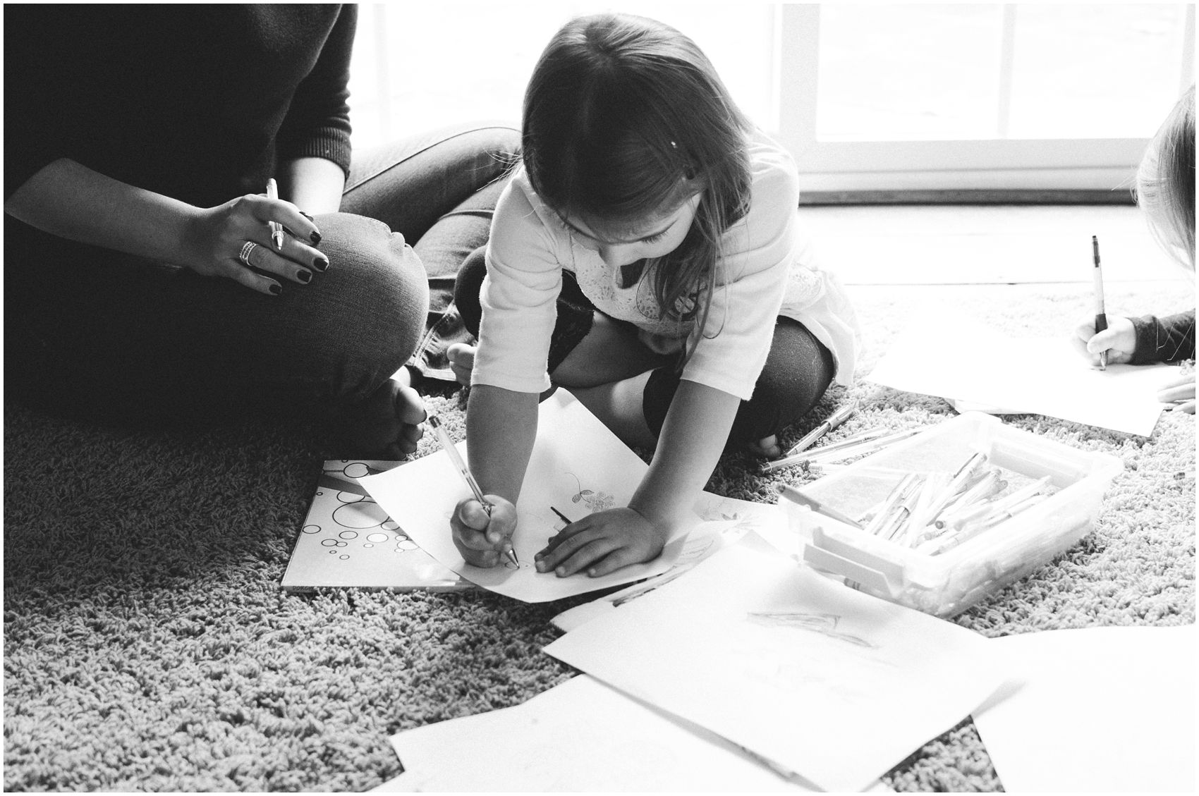 little girl coloring a paper on the floor next to her mom in Bergen County, NJ home