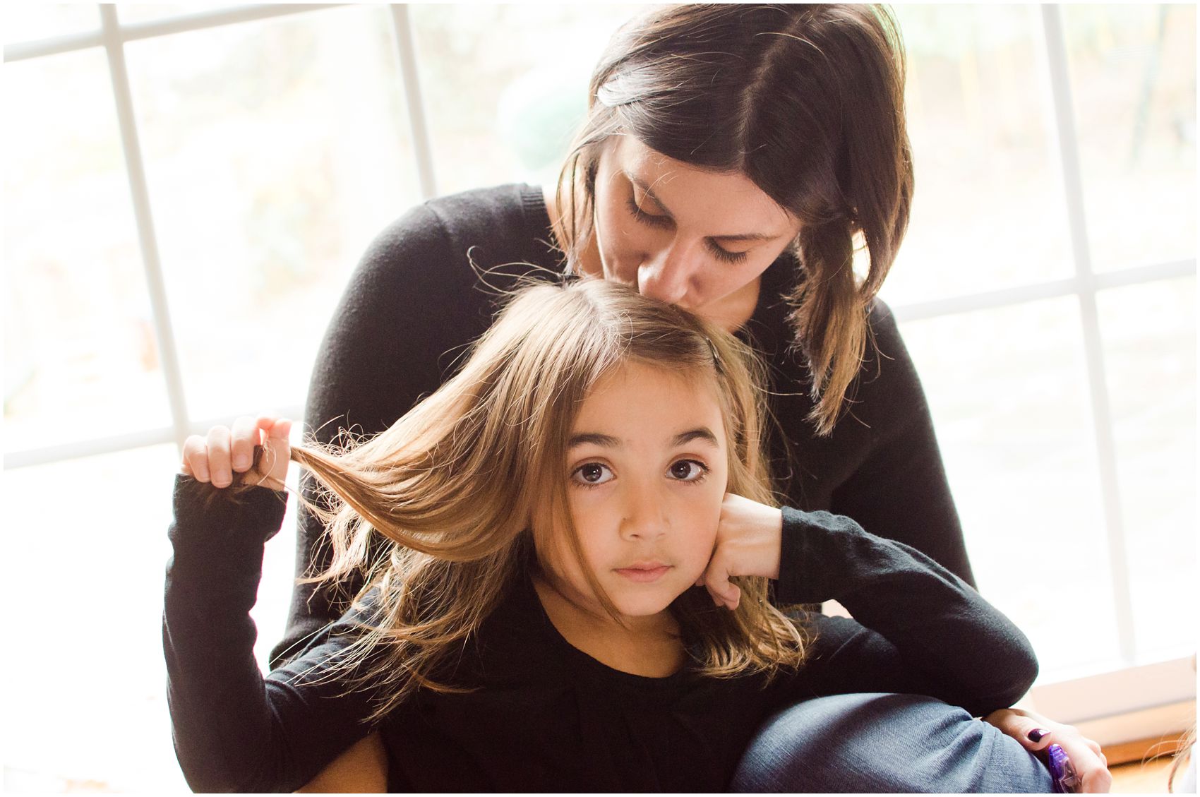 mom kissing her daughter's head as the daughter poses for the motherhood and family portrait in NJ