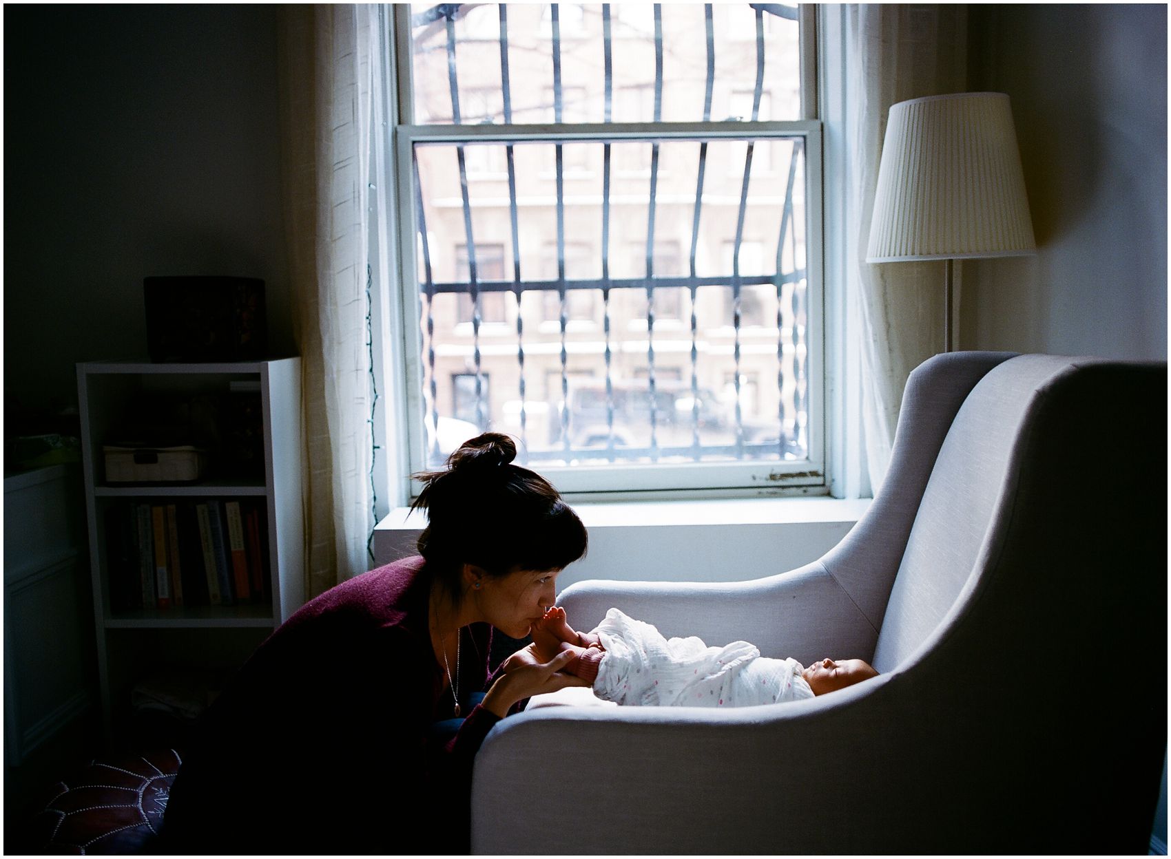mom kissing baby toes of her baby in her NYC home for the newborn photos