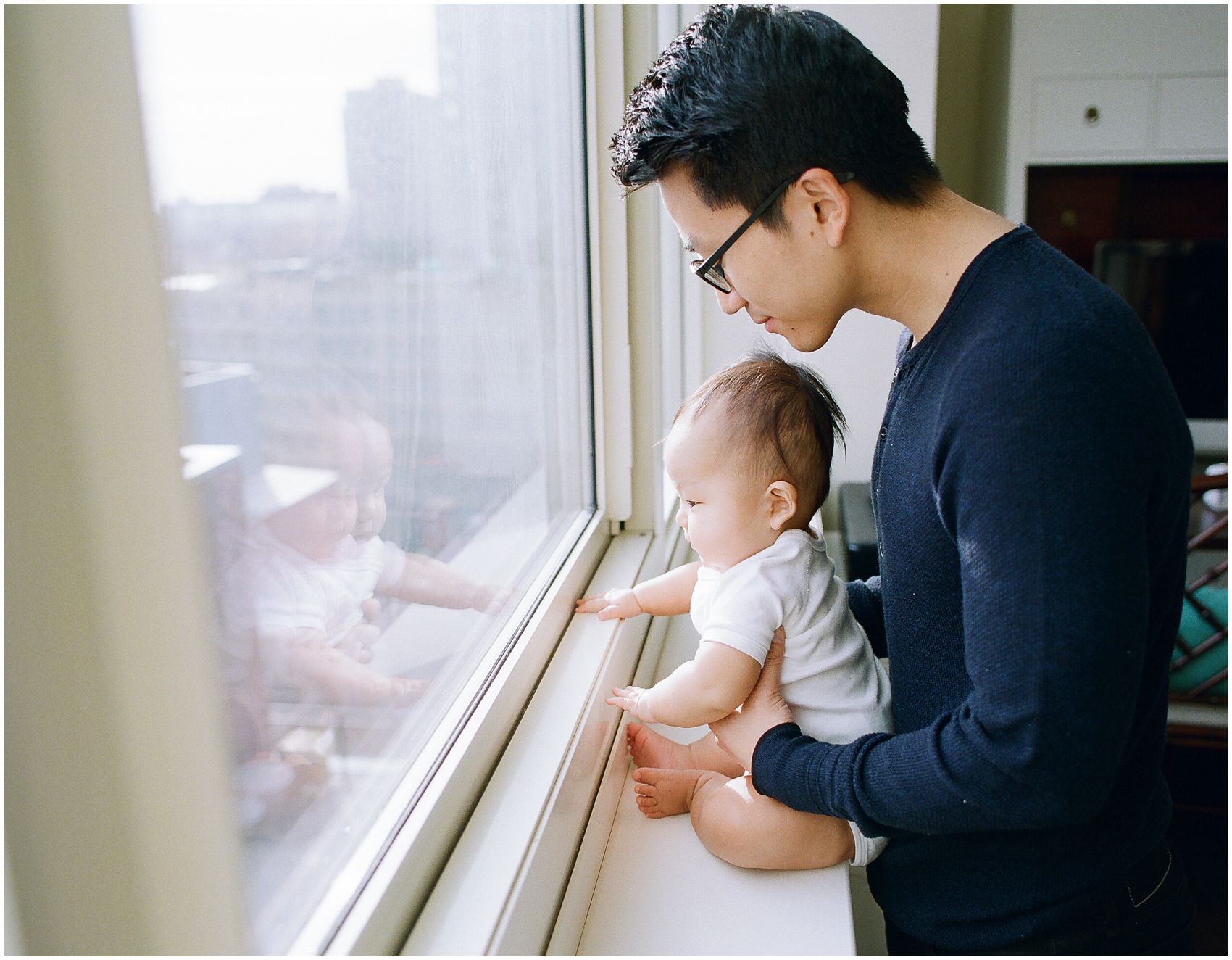 dad and 6 months baby boy looking out the window to NYC view