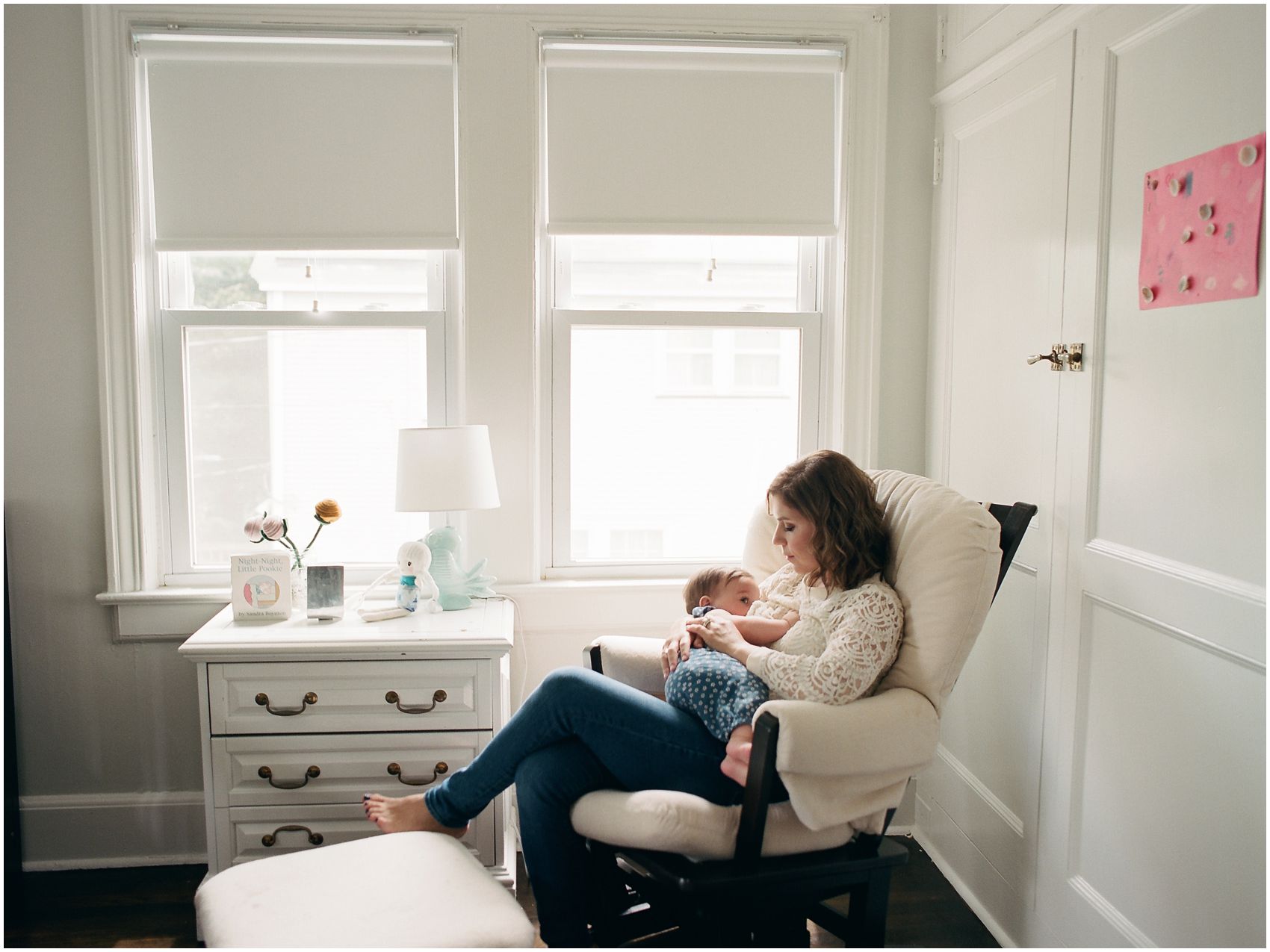 motherhood portrait of a mom breastfeeding baby girl in the rocking chair by the window in NJ