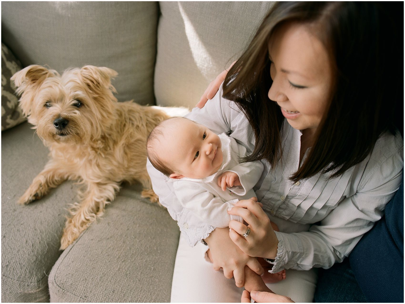 mom smiling and sitting with a baby and a family dog in NYC newborn photography session