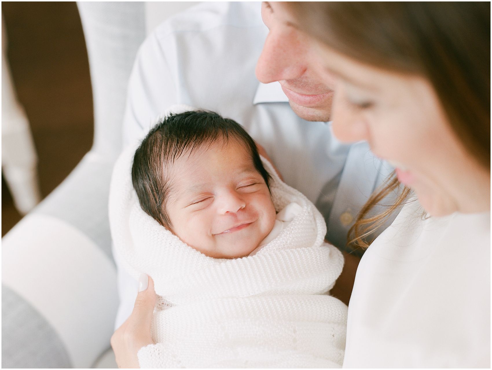 Newborn Photography NYC of a sleeping baby smiling in the arms of her parents
