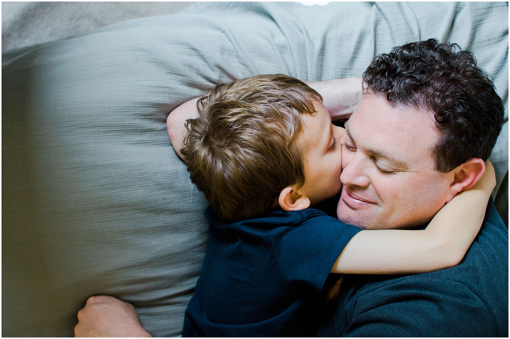 son snuggling with his dad and giving a hug during a fame family session at Hoboken NJ home