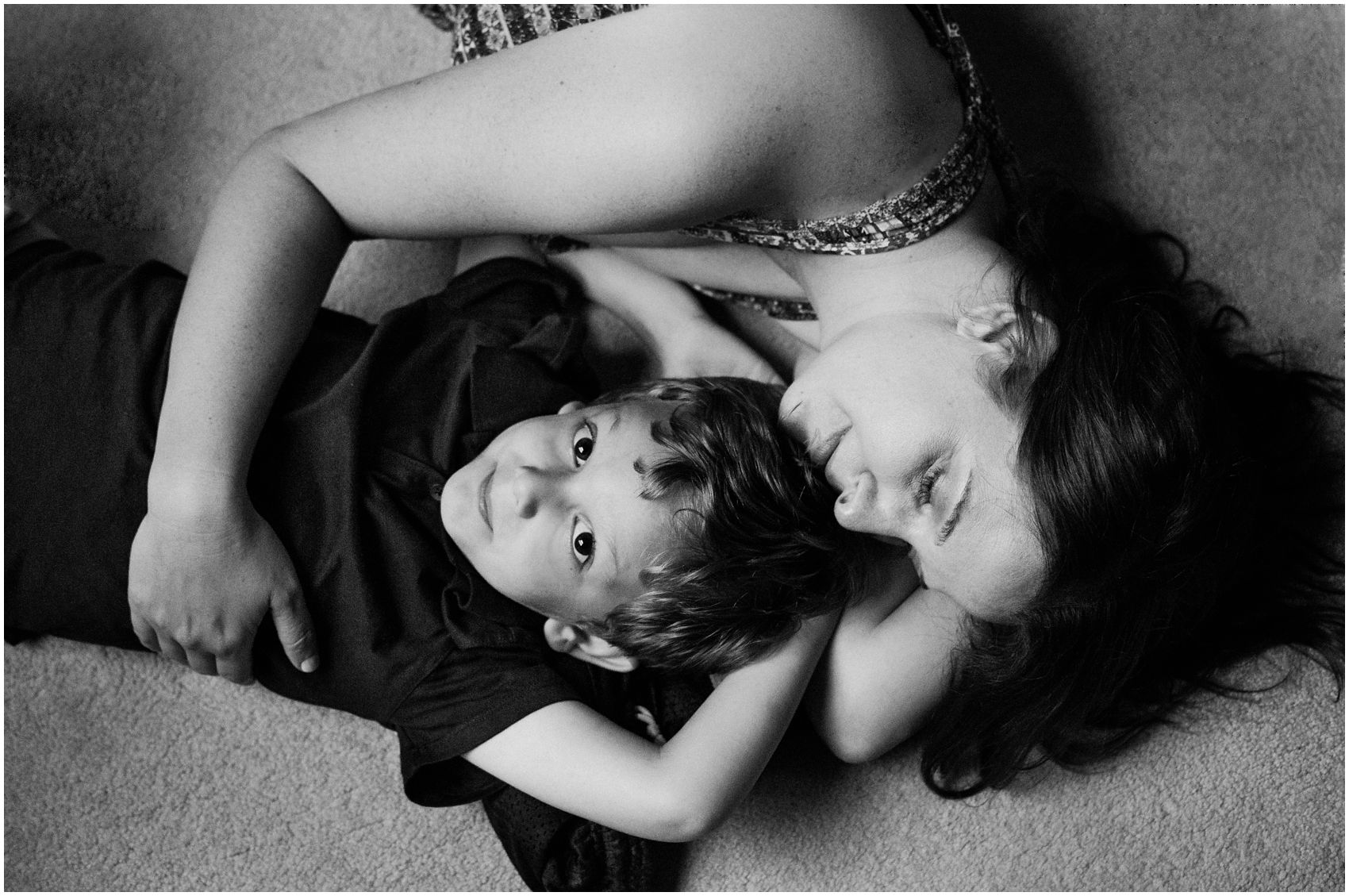 An artistic and emotive portrait of mom and son who are snuggling in bed of their NYC apartment