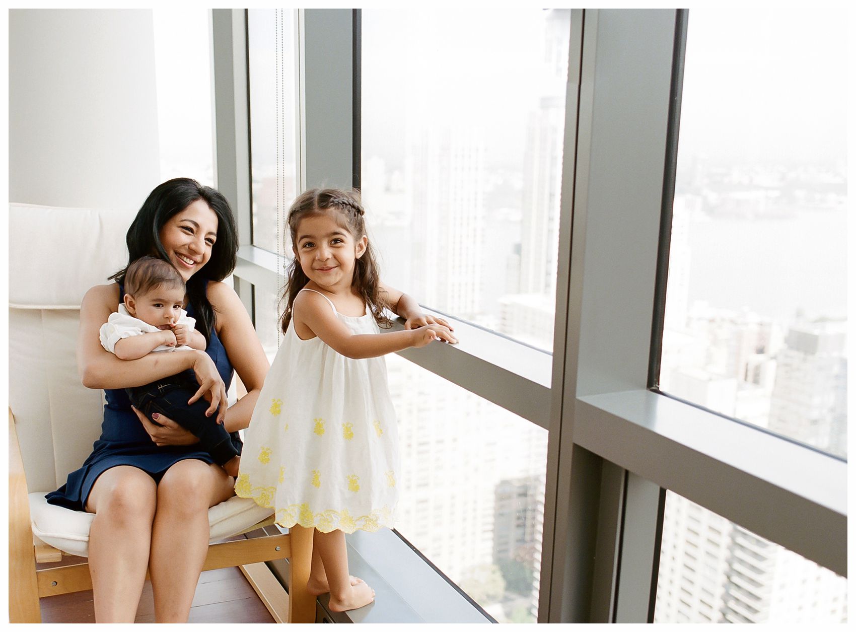 NYC Family Photographer Miriam Dubinsky shares tips on which portrait session is right for you and shows smiling mom and adorable kids by the big window at their NYC home