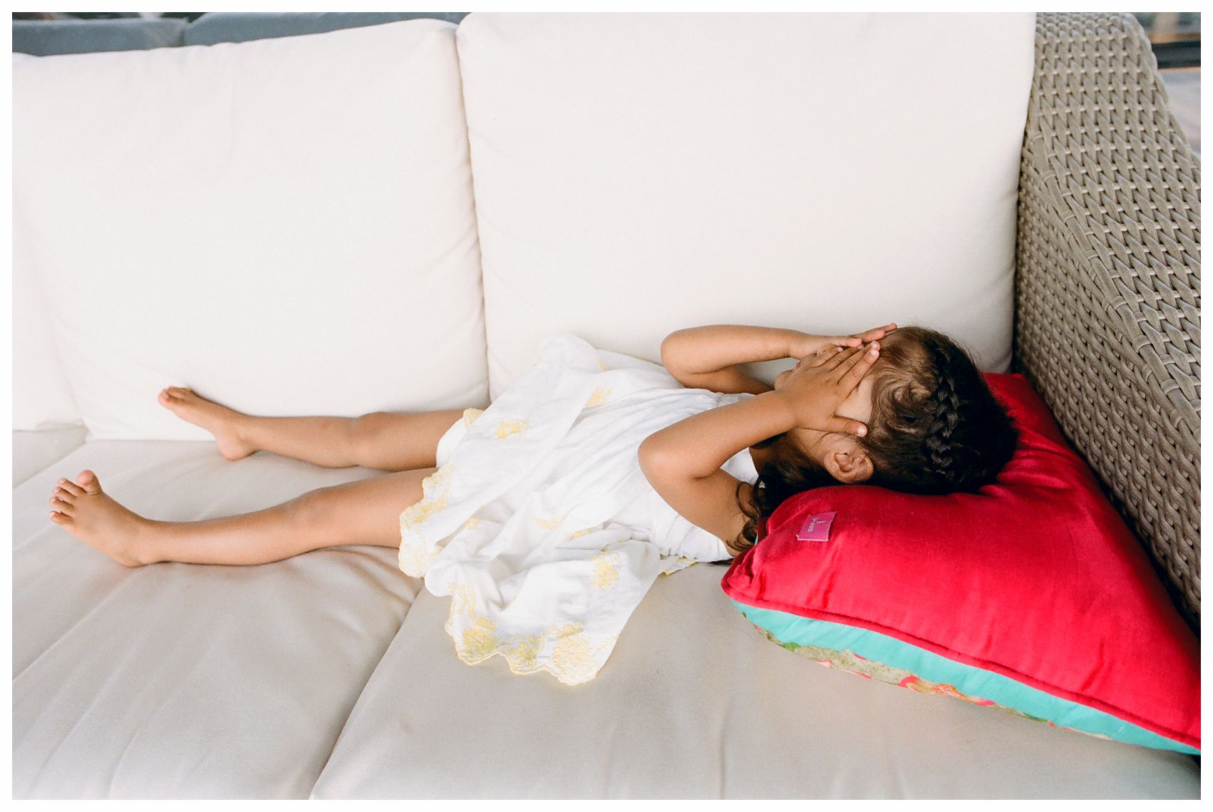 little girl in white dress laying on a couch and falling asleep during a family photo session in NYC