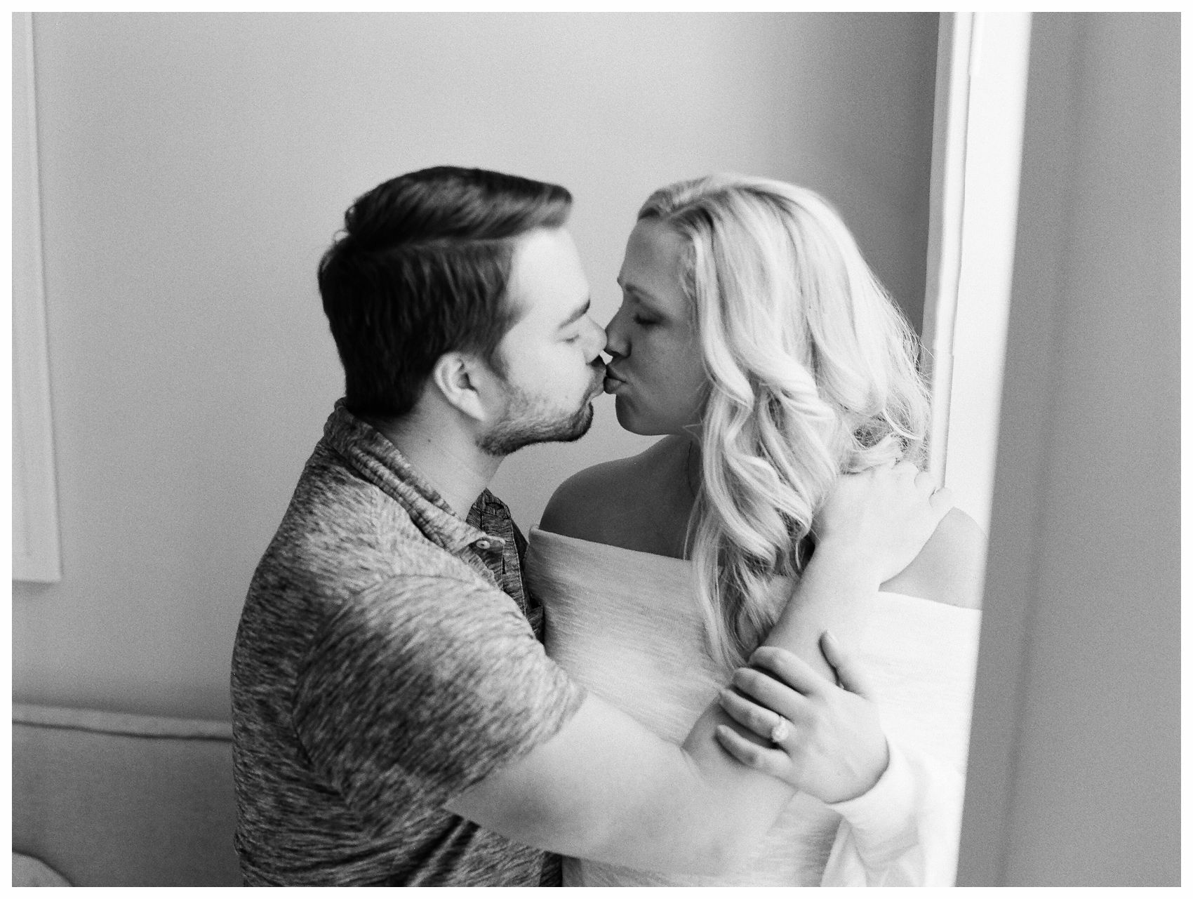 an elegant black and white portrait of a couple sharing a kiss and smooching in their NYC apartment