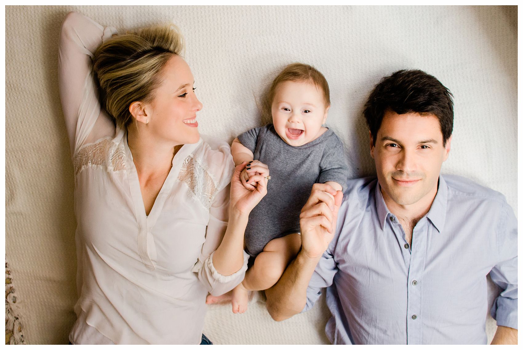 mom and dad laying on the bed with baby smiling in Hoboken