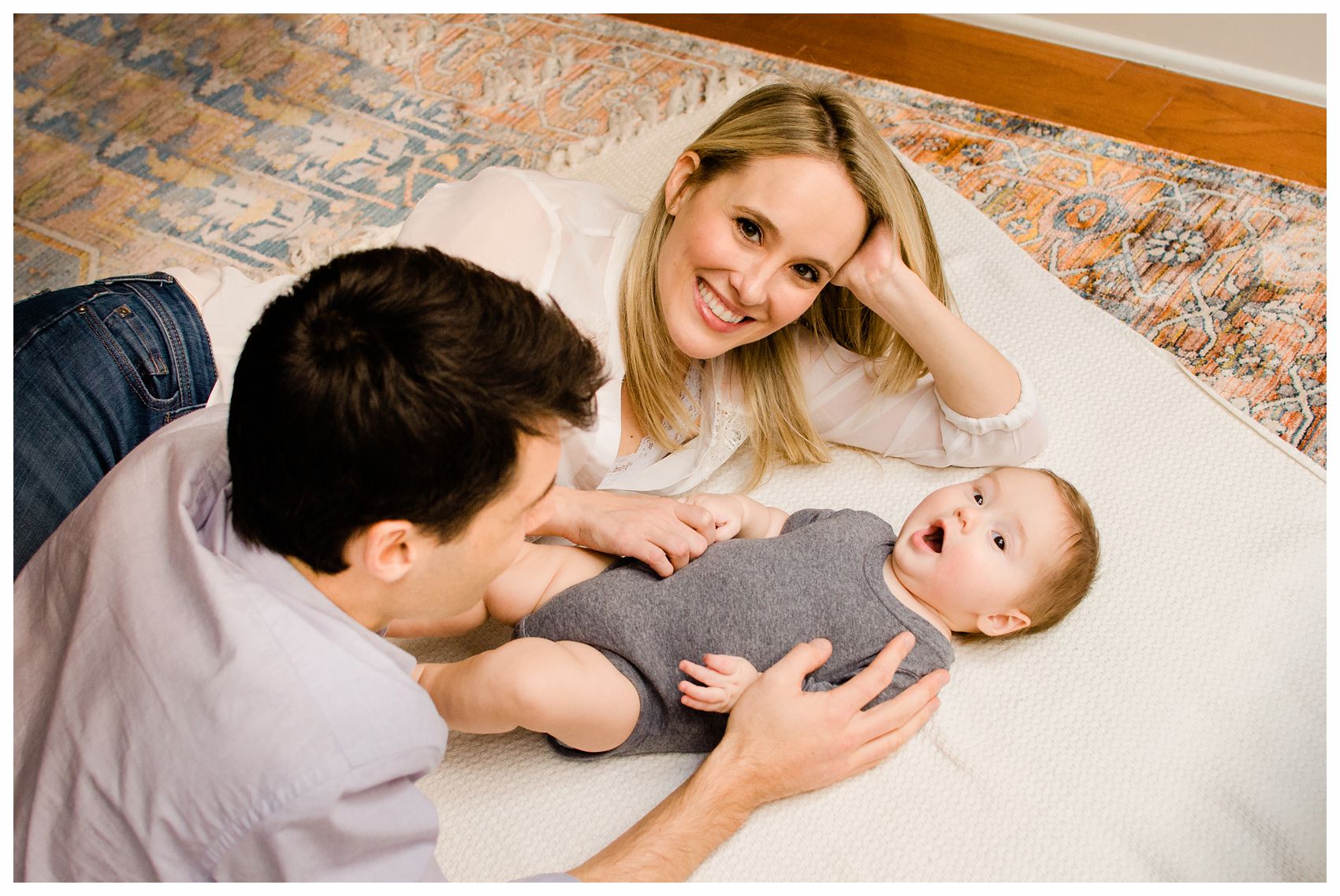 5 months curious baby relaxing on the floor with smiling mom and dad in Hoboken