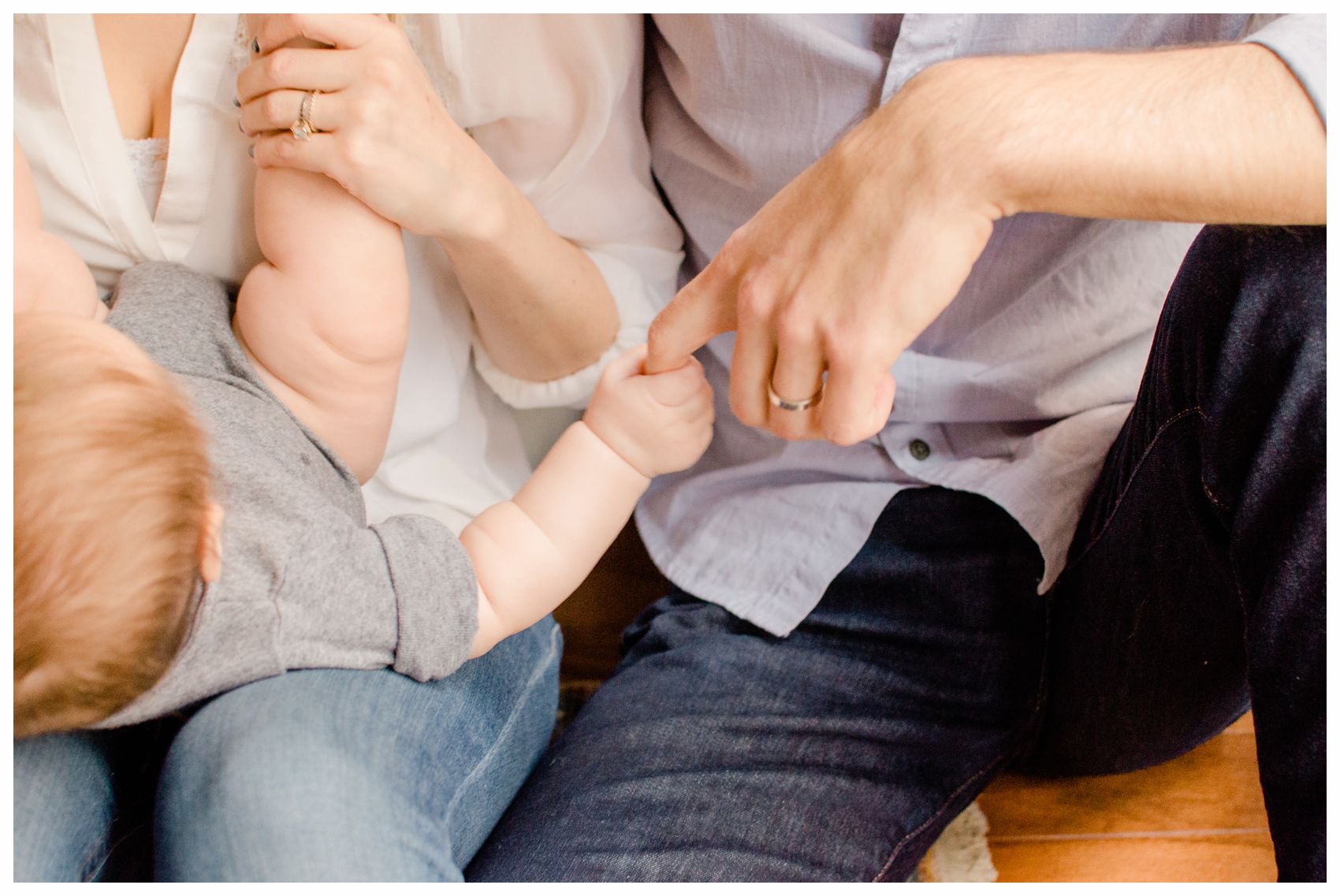 a closeup baby is holding dad's finger and mom is holding her baby chubby feet in Hoboken NJ