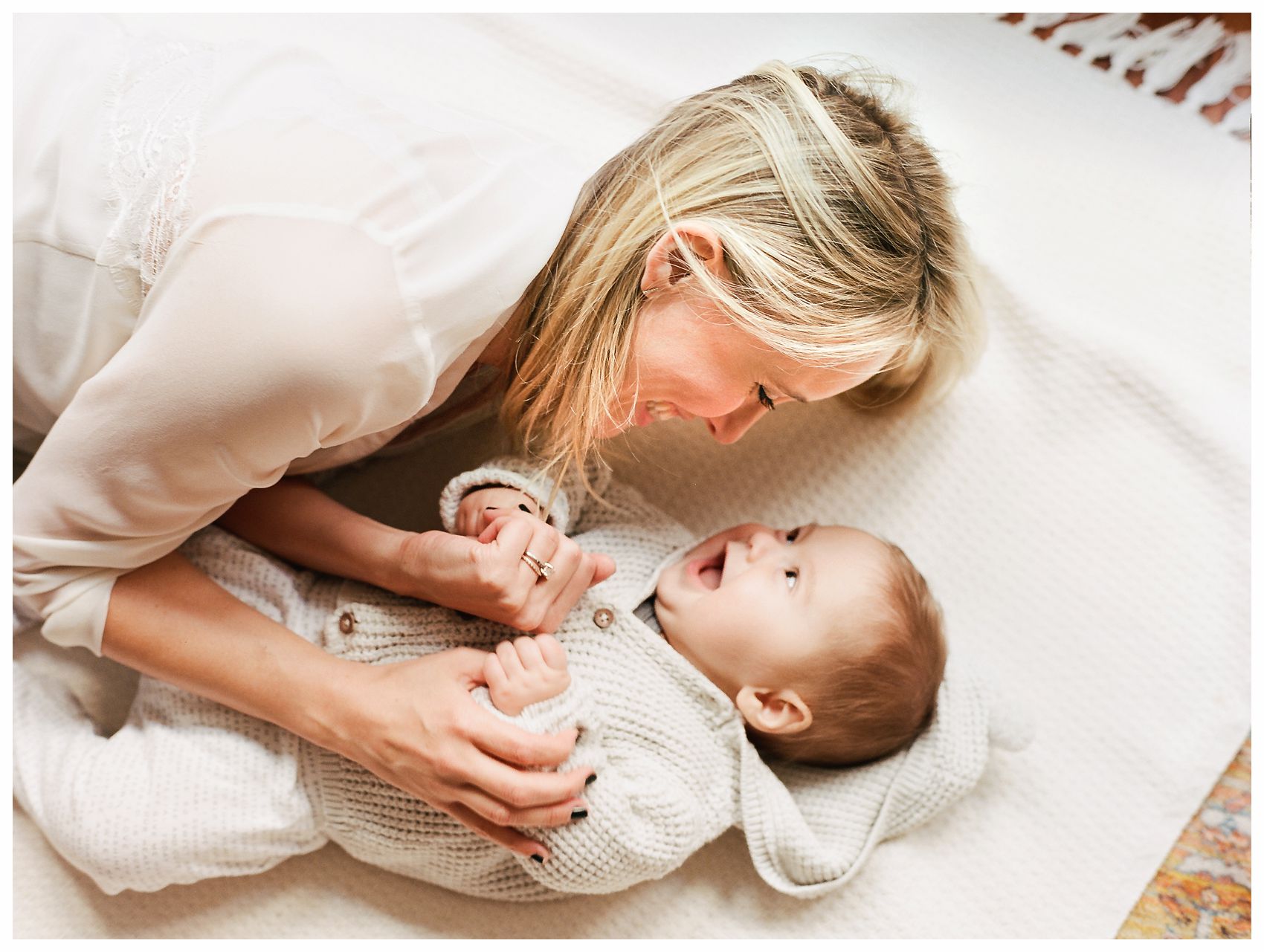 mom laughing with her baby boy on a white blanket in Hoboken NJ