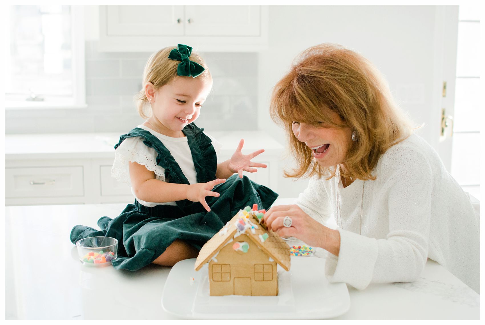 little girl building a gingerbread house with her grandmother for the holiday