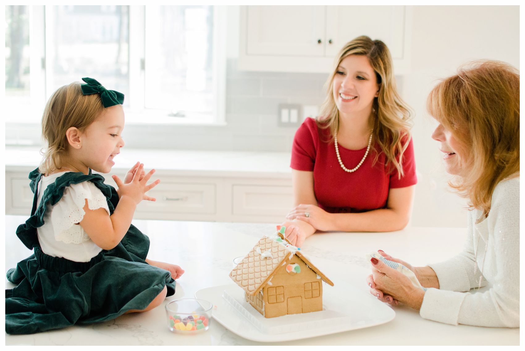 mom daughter and granddaughter building a gingerbread house