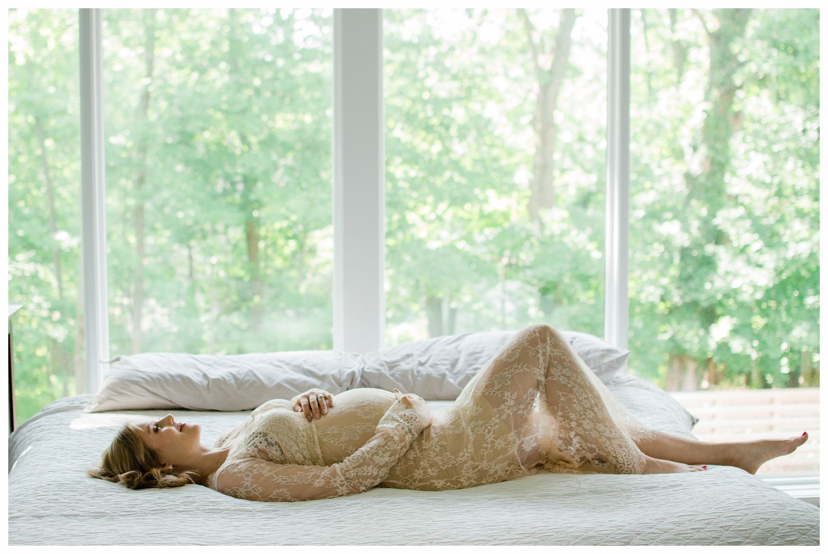 pregnant mom laying blissfully on her bed with trees in the background 
